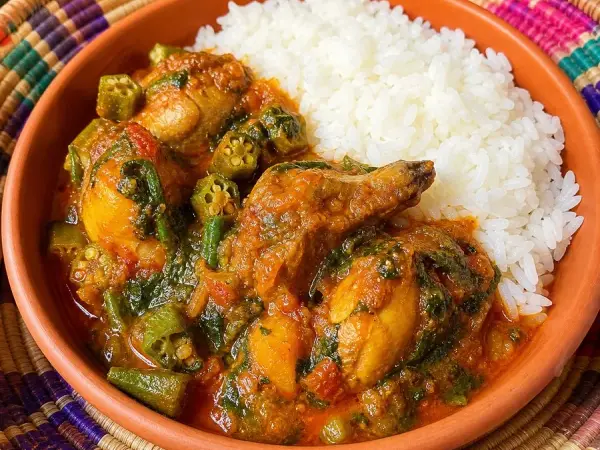 Angolan-inspired Moamba Chicken with rice in a terracotta bowl
