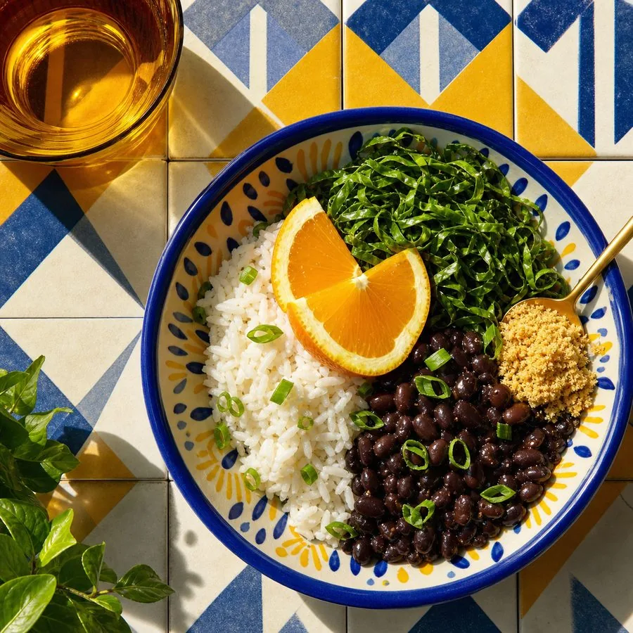 Brazilian black bean bowl with garlic rice, collard greens, orange wedges, and cassava farofa