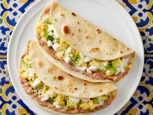 Folded flour tortillas with mashed beans, eggs, avocado and cheese